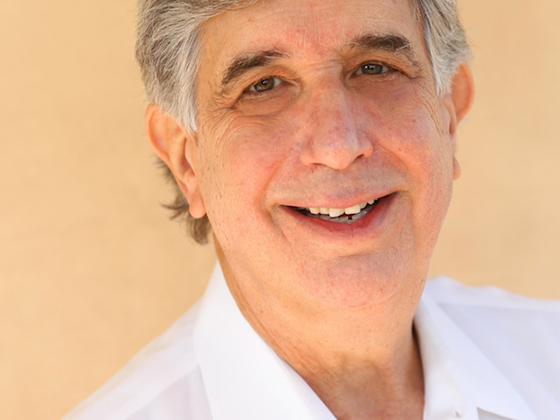 Smiling headshot of Rabbi Lee Bycel against a light orange background 